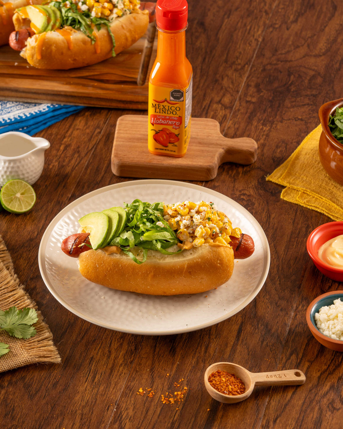 Delicioso elote hot dog con topping de elote amarillo, aguacate en rodajas, lechuga y bañado de Salsa México Lindo Habanero Rojo®.