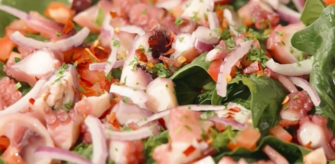 Riquísimo platillo de ensalada de pulpo a la brasa con cubitos de tomate, cebolla morada y chile quebrado en una cama de hojas de espinacas, salseado con la rica Salsa México Lindo Habanero Tatemado.