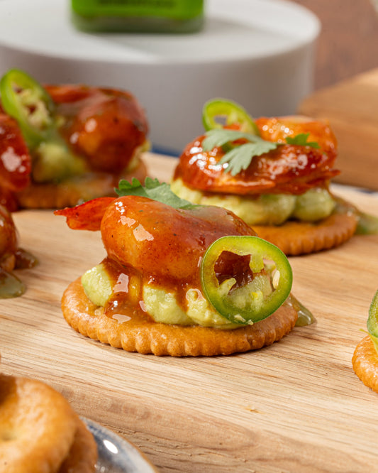 Exquisitos Bocaditos de Camarón, preparados con una salsa de adobo; galleta saladita de base, guacamole, camarones adobados decorado con una rodaja de chile serrano y salseado con Salsa México Lindo Habanero Verde®️