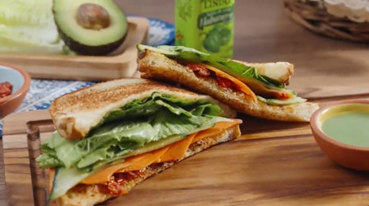 Delicioso sándwich vegetariano con queso y lechuga coronado con Salsa México Lindo Habanero Verde®