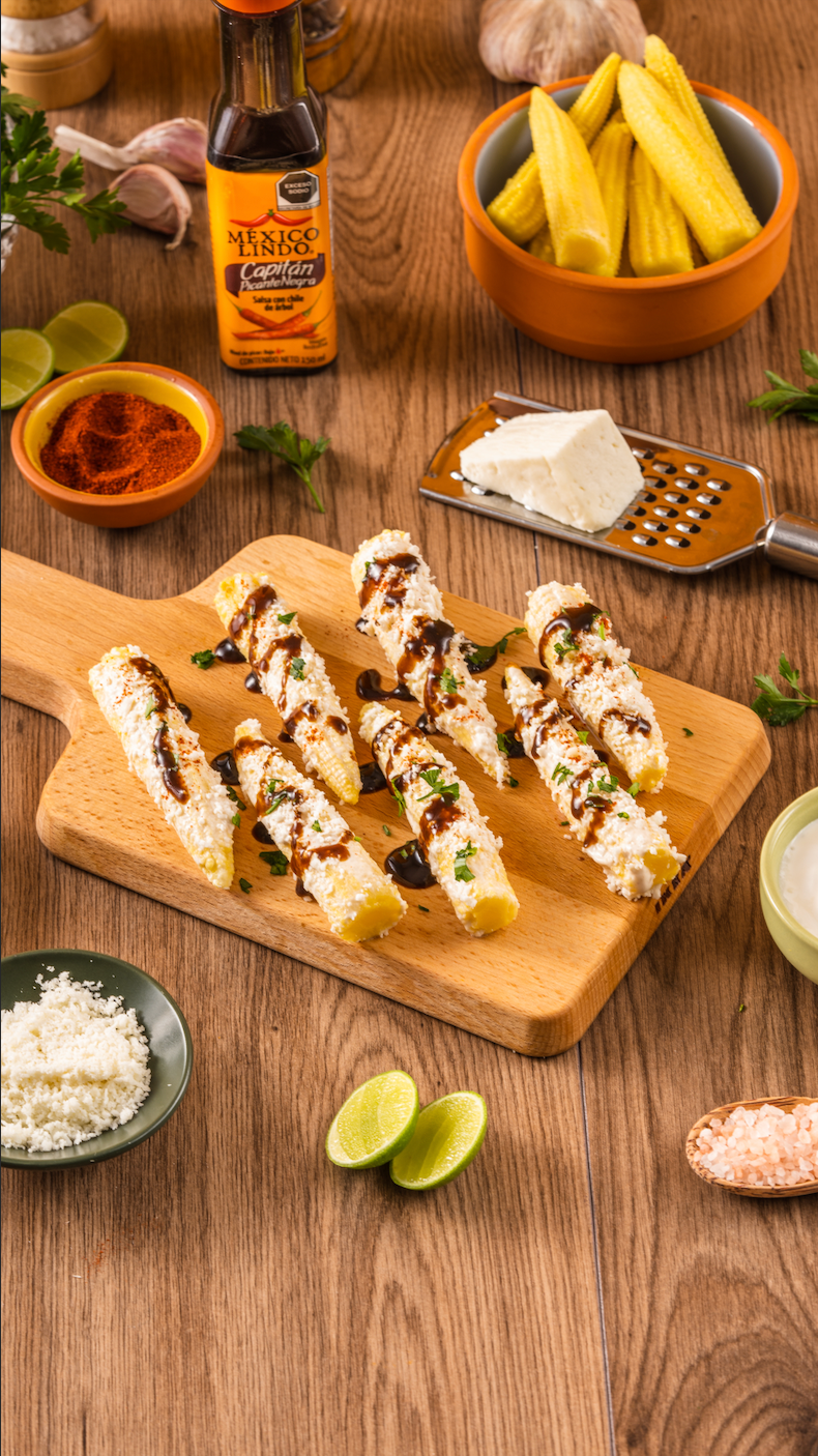 Elotitos baby cubietos en crema y queso, decorados con perejil fresco picado, bañados en Salsa México Lindo Capitán Picante Negra®️ y acompados de limón 